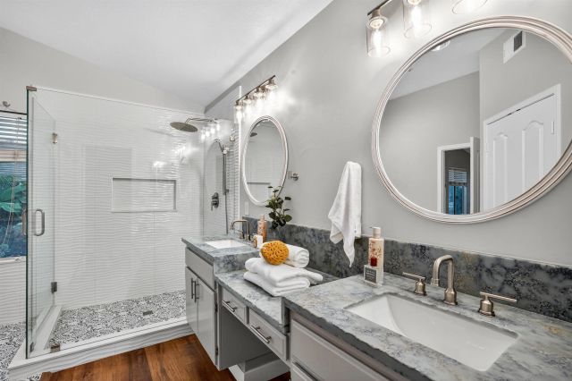 a bathroom with a granite countertop double vanity sink and a mirror