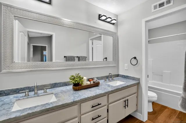 a bathroom with a granite countertop sink mirror and toilet