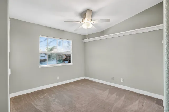 an empty room with a window and a fan