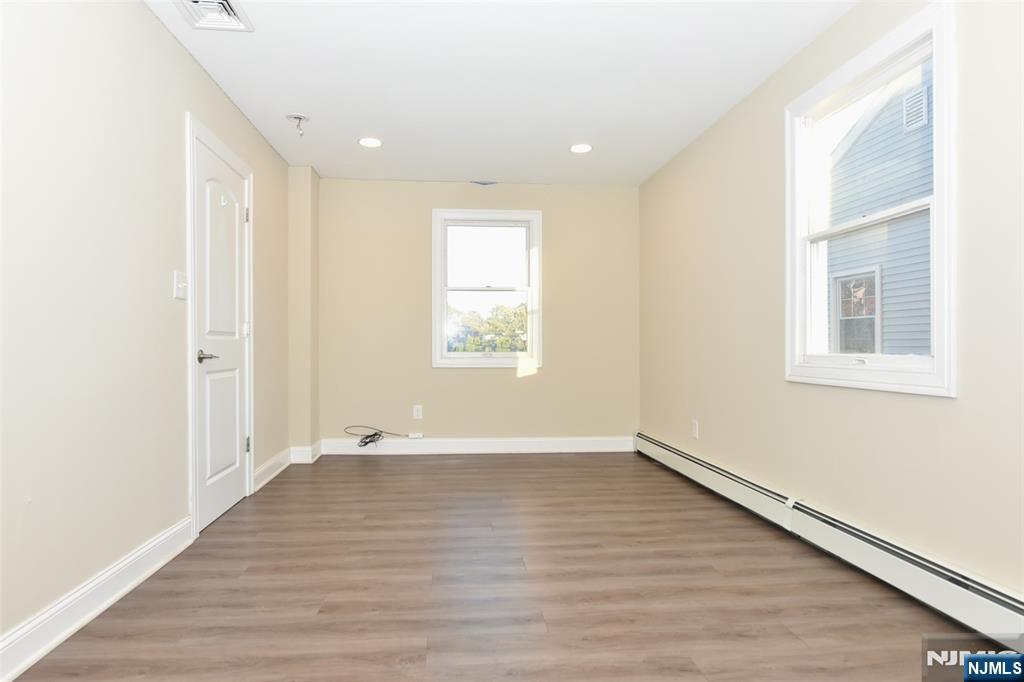 105 Parkway Rochelle Park, NJ 07662 - Photo 13 of 22 an empty room with wooden floor and windows