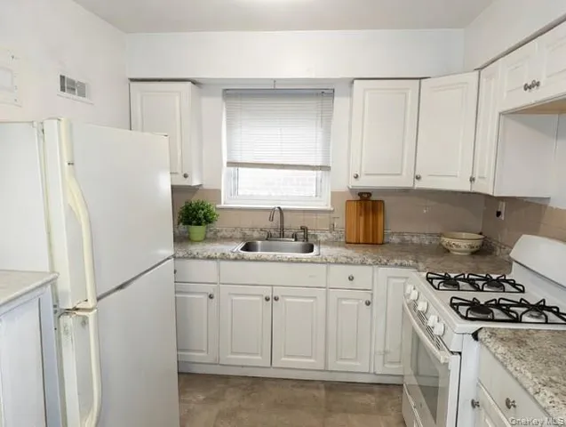 a kitchen with white cabinets and white appliances