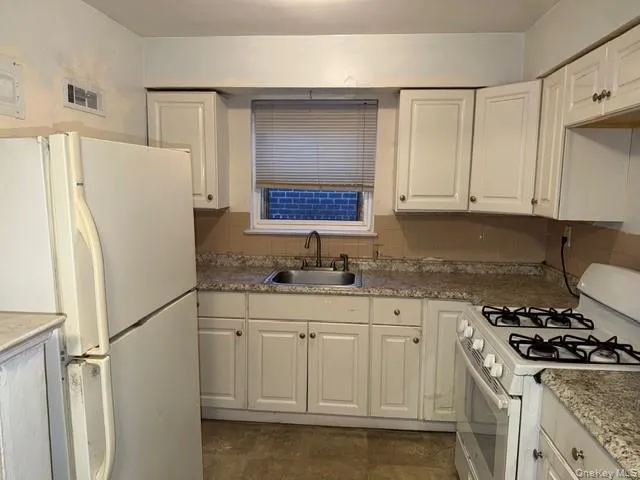 a kitchen with granite countertop a sink stove and refrigerator