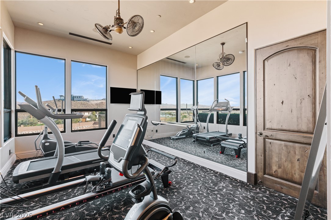 1123 Christian Road Henderson, NV 89002 - Photo 30 of 94 A well-lit exercise room with a mirrored wall, offering panoramic desert landscape views through large windows.