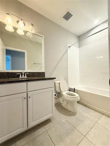 a bathroom with a granite countertop sink a toilet and a mirror