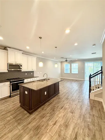 a large kitchen with stainless steel appliances granite countertop a stove and a wooden floors