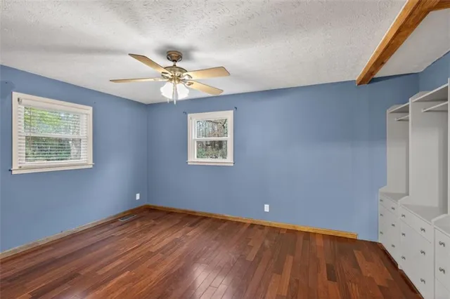 a view of a big room with wooden floor and windows