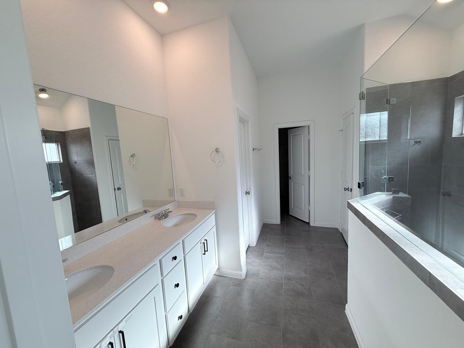 160 Venti Cove Georgetown, TX 78628 - Photo 30 of 40 a bathroom with a granite countertop sink a large mirror and shower