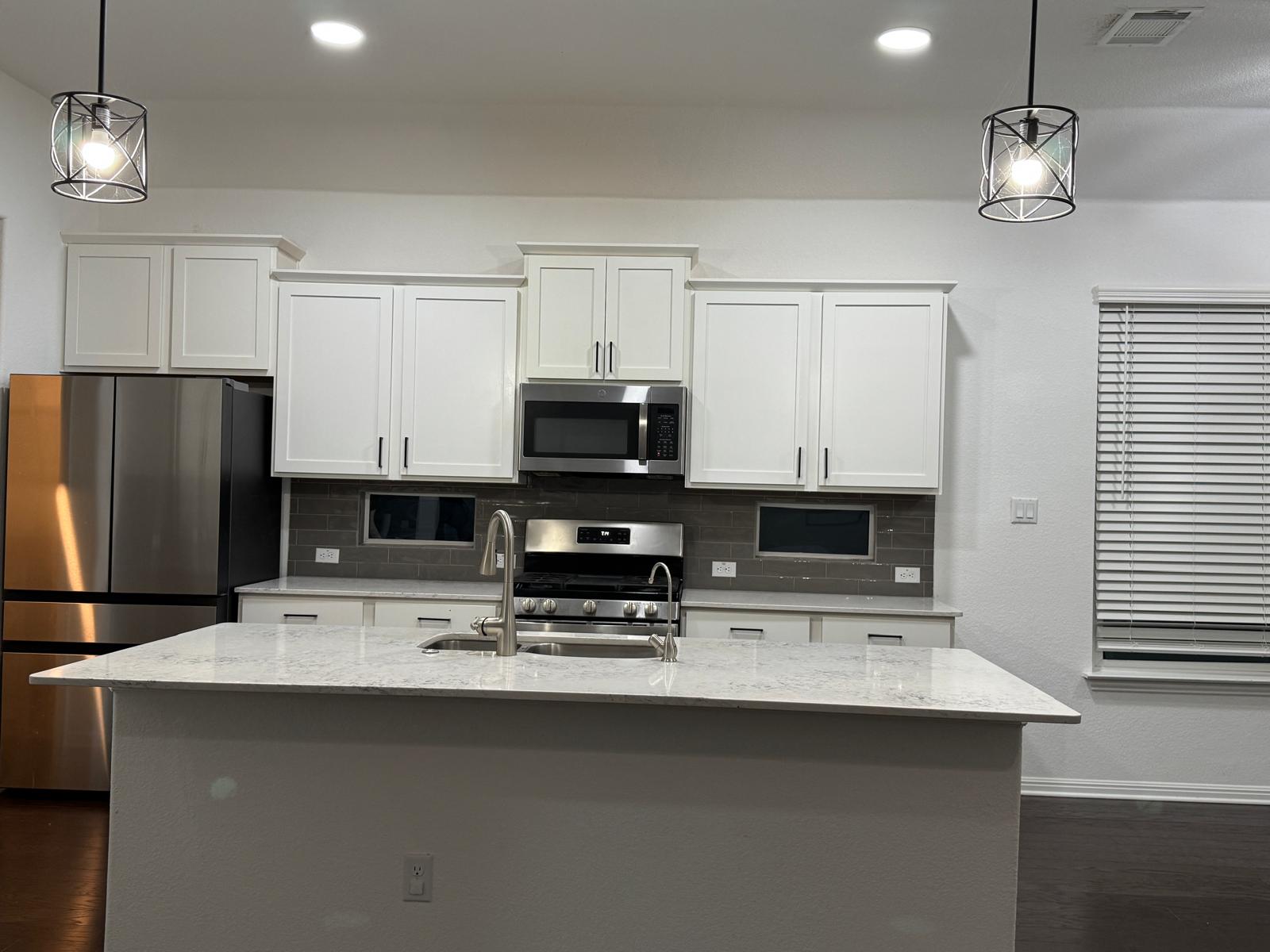 160 Venti Cove Georgetown, TX 78628 - Photo 5 of 40 a kitchen with stainless steel appliances a sink a stove a microwave a refrigerator a center island and cabinets