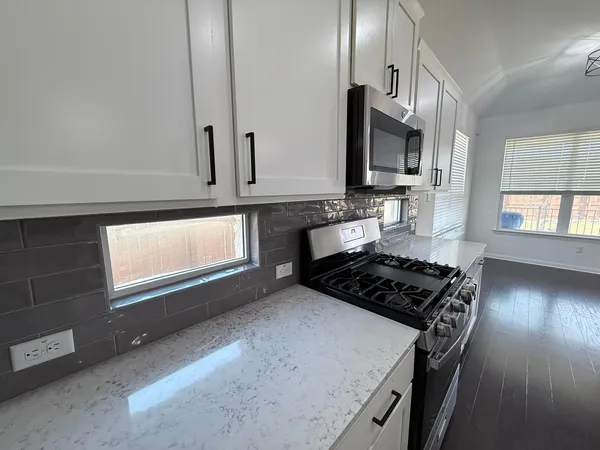 a kitchen with granite countertop a stove a sink and a microwave