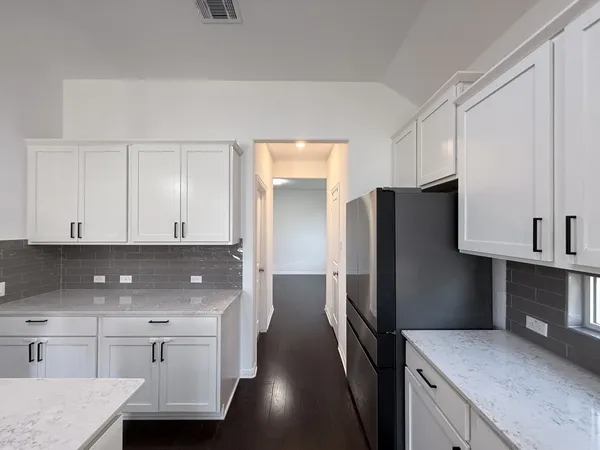 a kitchen with stainless steel appliances granite countertop a refrigerator a sink and white cabinets