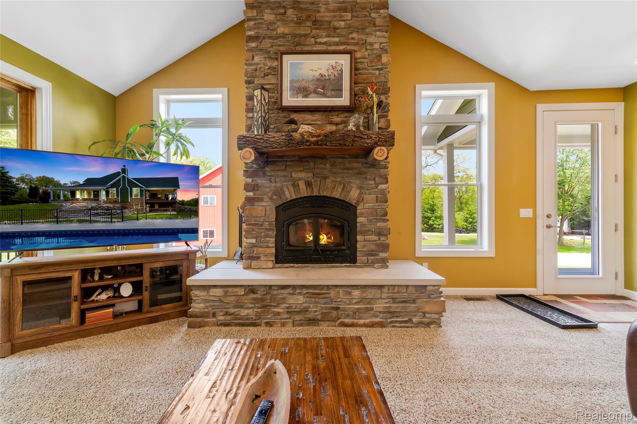13085 Rohn Road Fenton, MI 48430 - Photo 10 of 52 Living area with a stone fireplace, plenty of natural light, vaulted ceiling, and carpet floors
