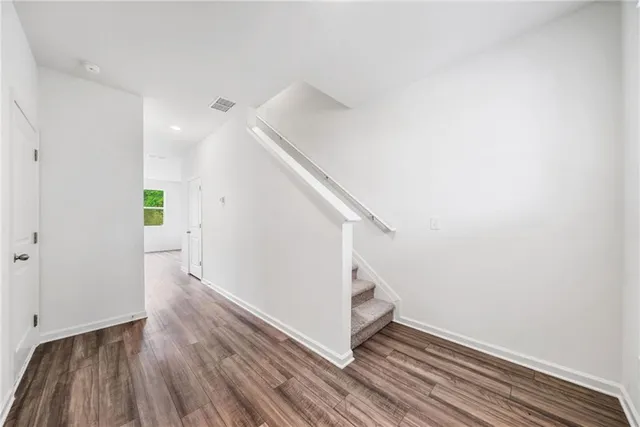 a view of a hallway with wooden floor and staircase