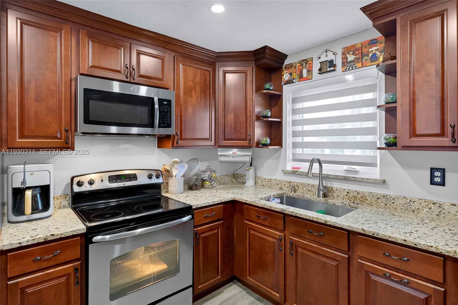 20810 Southwest 125th Court Road Miami, FL 33177 - Photo 17 of 52 a kitchen with granite countertop a sink a stove a microwave and cabinets