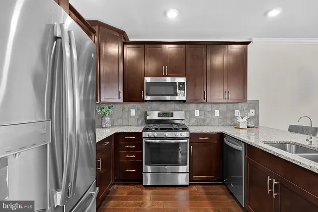 a kitchen with stainless steel appliances granite countertop a stove a sink and a microwave