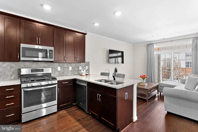 a kitchen with stainless steel appliances granite countertop wooden cabinets a sink dishwasher a stove and a refrigerator with wooden floor