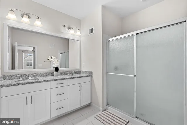 a bathroom with a granite countertop sink two mirror and a shower