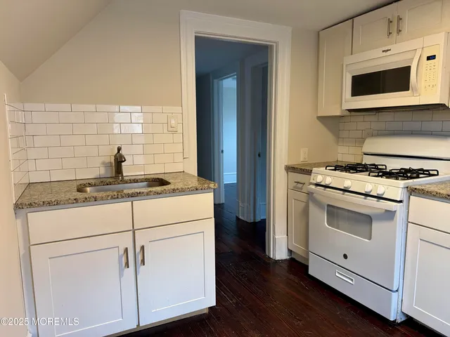 a kitchen with stainless steel appliances white cabinets and a stove top oven