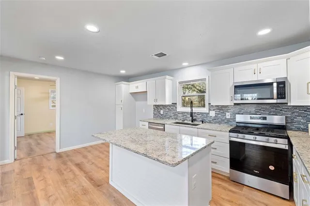 a kitchen with stainless steel appliances granite countertop a stove a sink and a microwave