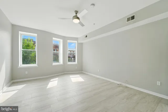 an empty room with windows and ceiling fan