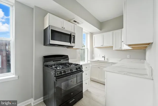 a kitchen with stainless steel appliances granite countertop white cabinets and a stove a oven with white countertops