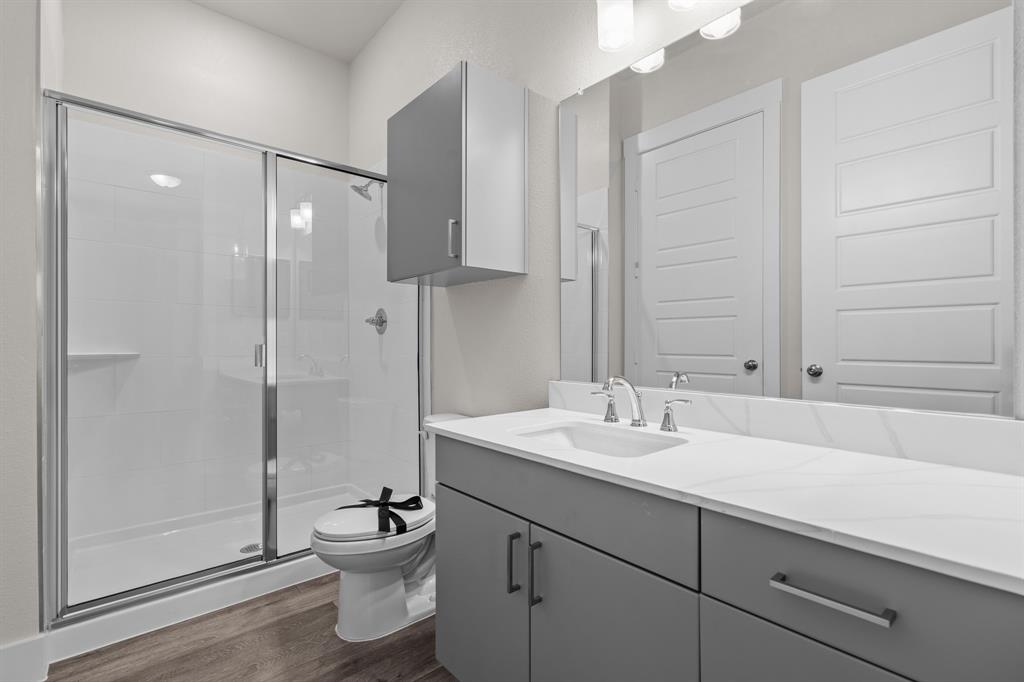 3280 Ganzer Road West, Unit 127B Denton, TX 76207 - Photo 17 of 22 a bathroom with a toilet a sink and a mirror