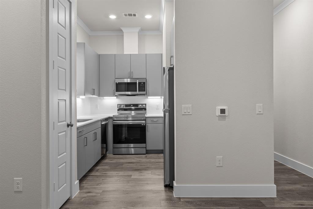 3280 Ganzer Road West, Unit 127B Denton, TX 76207 - Photo 3 of 22 a kitchen with cabinets stainless steel appliances and wooden floor