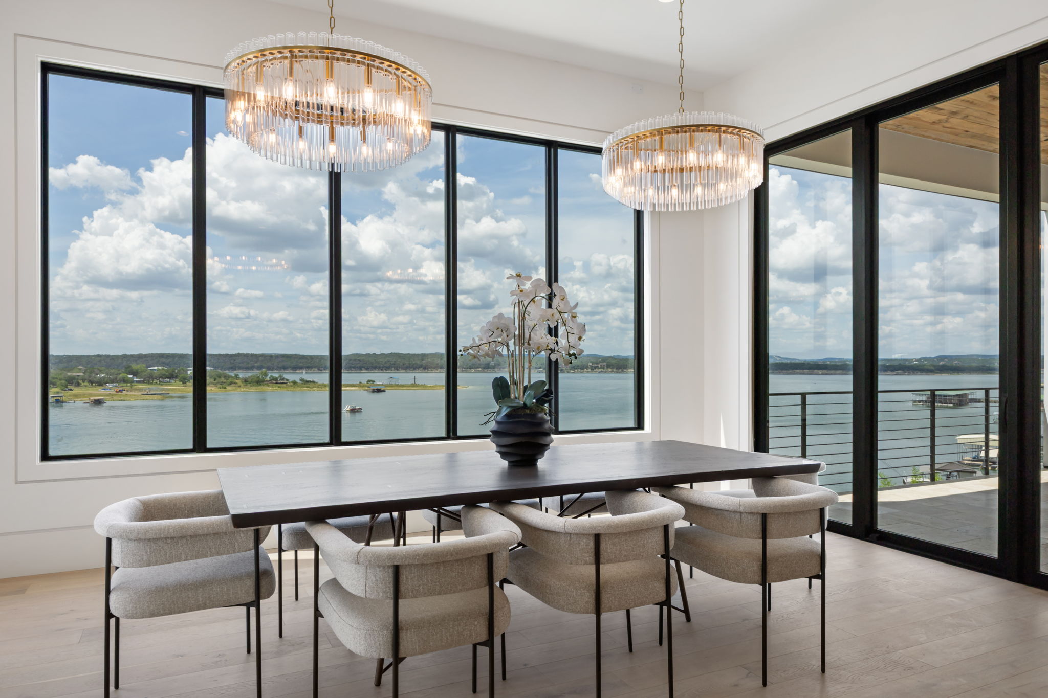 1496 Buffalo Gap Road Lakeway, TX 78734 - Photo 5 of 37 Grand chandeliers illuminate this dining area, featuring vast windows showcasing panoramic lake and hillside views.
