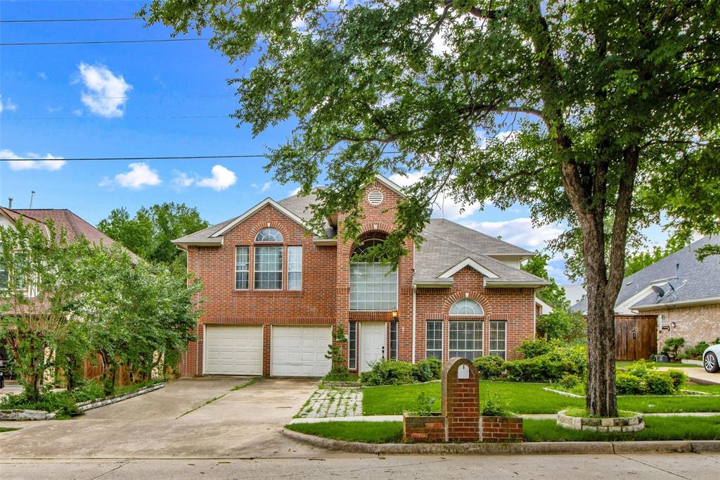 Brick-clad residence featuring a two-car garage, arched windows, and a prominent front entry with sidelights