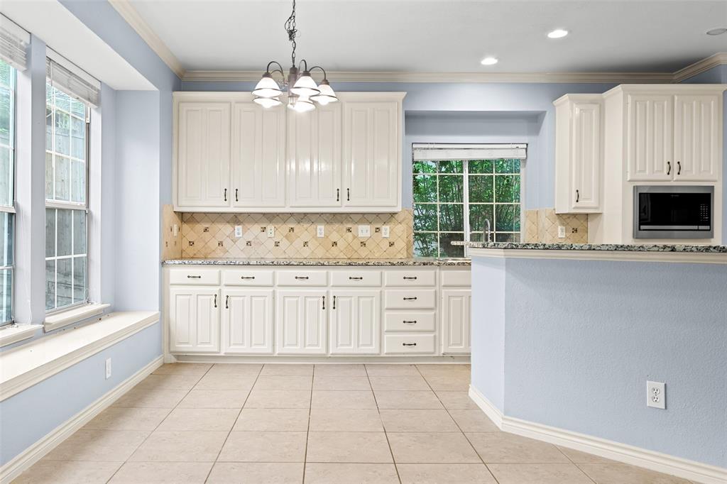 2604 Ridgewood Drive Plano, TX 75074 - Photo 12 of 35 Kitchen featuring white cabinetry with dark hardware, granite countertops, and a patterned tile backsplash
