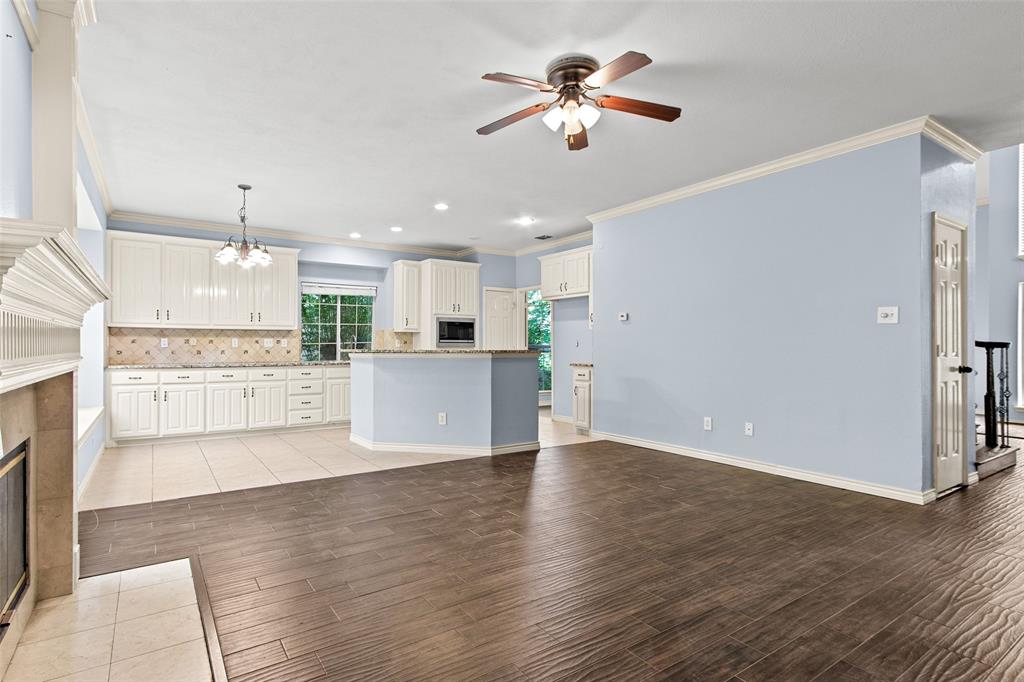 2604 Ridgewood Drive Plano, TX 75074 - Photo 13 of 35 Expansive living area with wood-finish flooring, a ceiling fan, and a fireplace with a stone surround