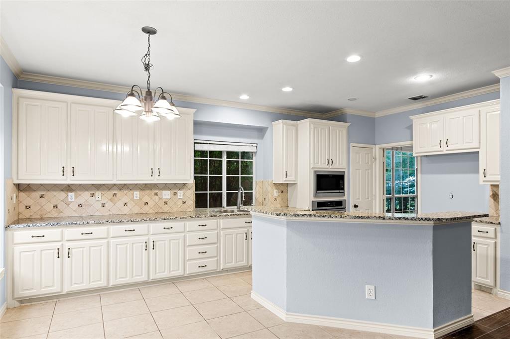 2604 Ridgewood Drive Plano, TX 75074 - Photo 14 of 35 Spacious kitchen featuring extensive white cabinetry, granite countertops, a built-in microwave, tile backsplash, and tile flooring