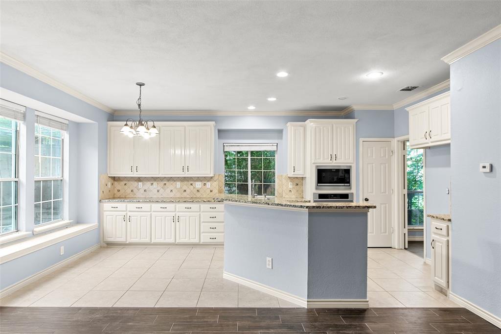 2604 Ridgewood Drive Plano, TX 75074 - Photo 15 of 35 Kitchen featuring white paneled cabinetry, light-toned tile flooring, granite countertops, and a built-in microwave
