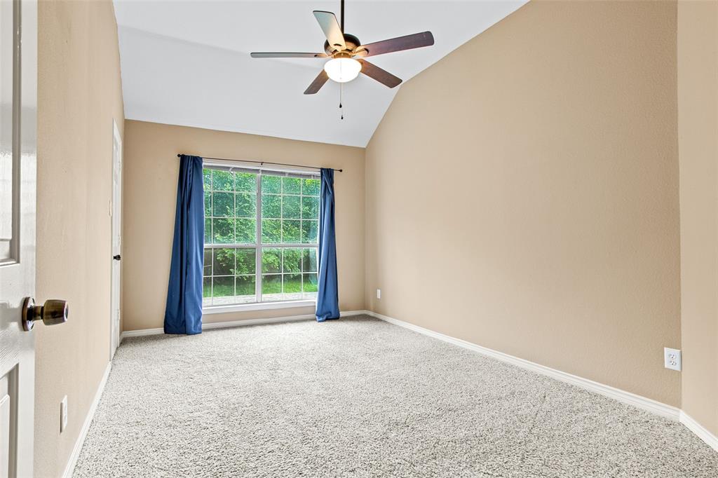 2604 Ridgewood Drive Plano, TX 75074 - Photo 24 of 35 Vaulted ceilings enhance this carpeted room featuring a large window with exterior foliage, a ceiling fan with light fixture, and neutral-toned walls
