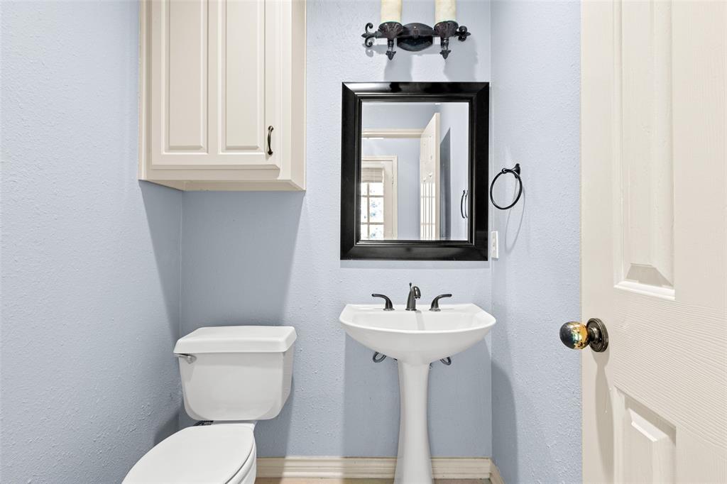 2604 Ridgewood Drive Plano, TX 75074 - Photo 29 of 35 Pedestal sink with black fixture, framed mirror, and wall-mounted sconce