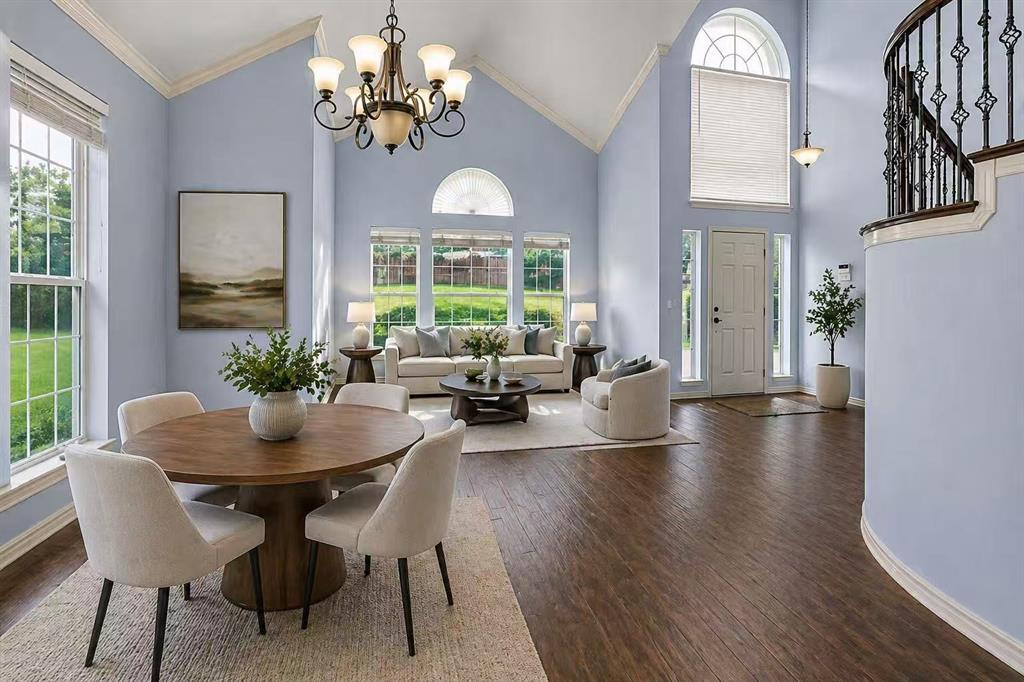 2604 Ridgewood Drive Plano, TX 75074 - Photo 6 of 35 Two-story living area with vaulted ceilings, large windows, wood-finish flooring, and a curved staircase featuring wrought iron balusters