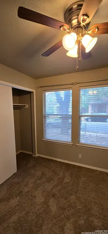 a view of an empty room with window and chandelier fan
