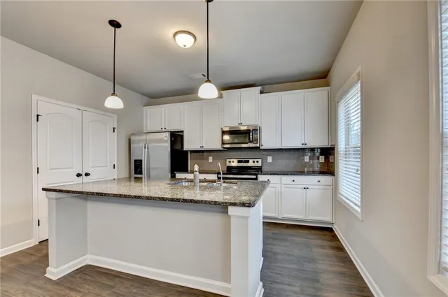 a kitchen with stainless steel appliances granite countertop a sink a stove a refrigerator a center island and cabinets