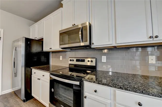 a kitchen with stainless steel appliances granite countertop white cabinets and a stove a refrigerator with white countertops