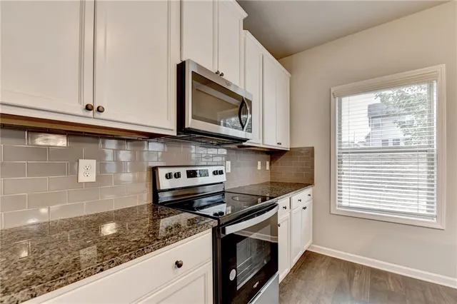 a kitchen with stainless steel appliances granite countertop a sink a stove and microwave
