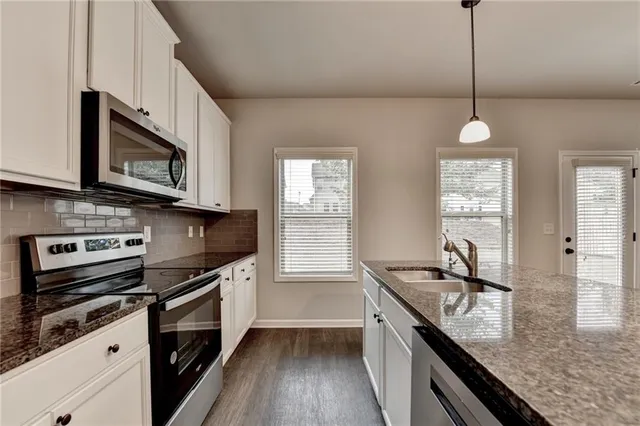 a kitchen with stainless steel appliances granite countertop a sink stove and microwave