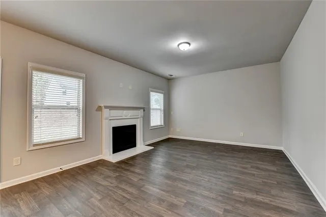an empty room with wooden floor fireplace and windows