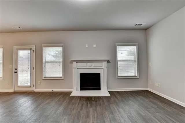 an empty room with wooden floor fireplace and windows