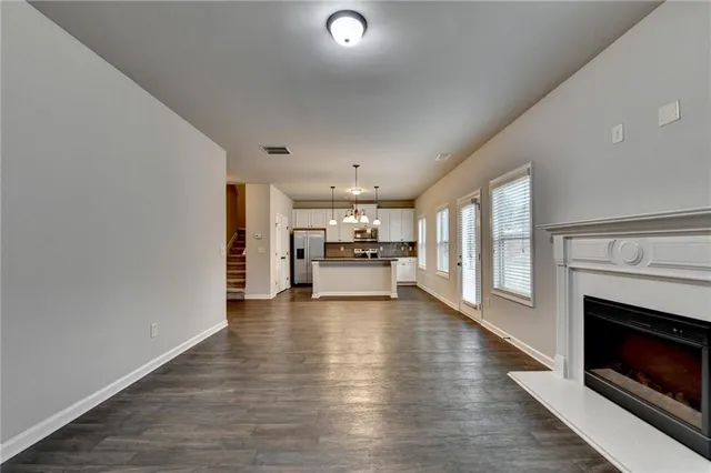 a view of an empty room and kitchen with a fireplace