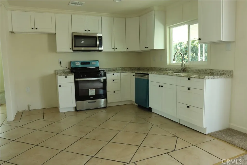 1855 East Riverside Drive, Unit 48 Ontario, CA 91761 - Photo 6 of 20 a kitchen with granite countertop white cabinets stainless steel appliances a sink and a window