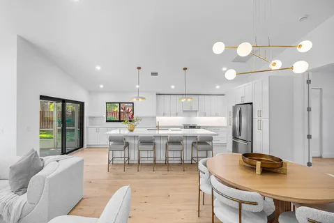 a living room with stainless steel appliances furniture a dining table and kitchen view