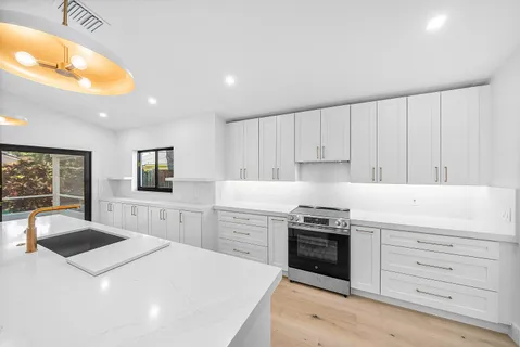 a kitchen with granite countertop white cabinets and stainless steel appliances