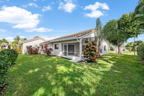 a backyard of a house with table and chairs plants and large tree