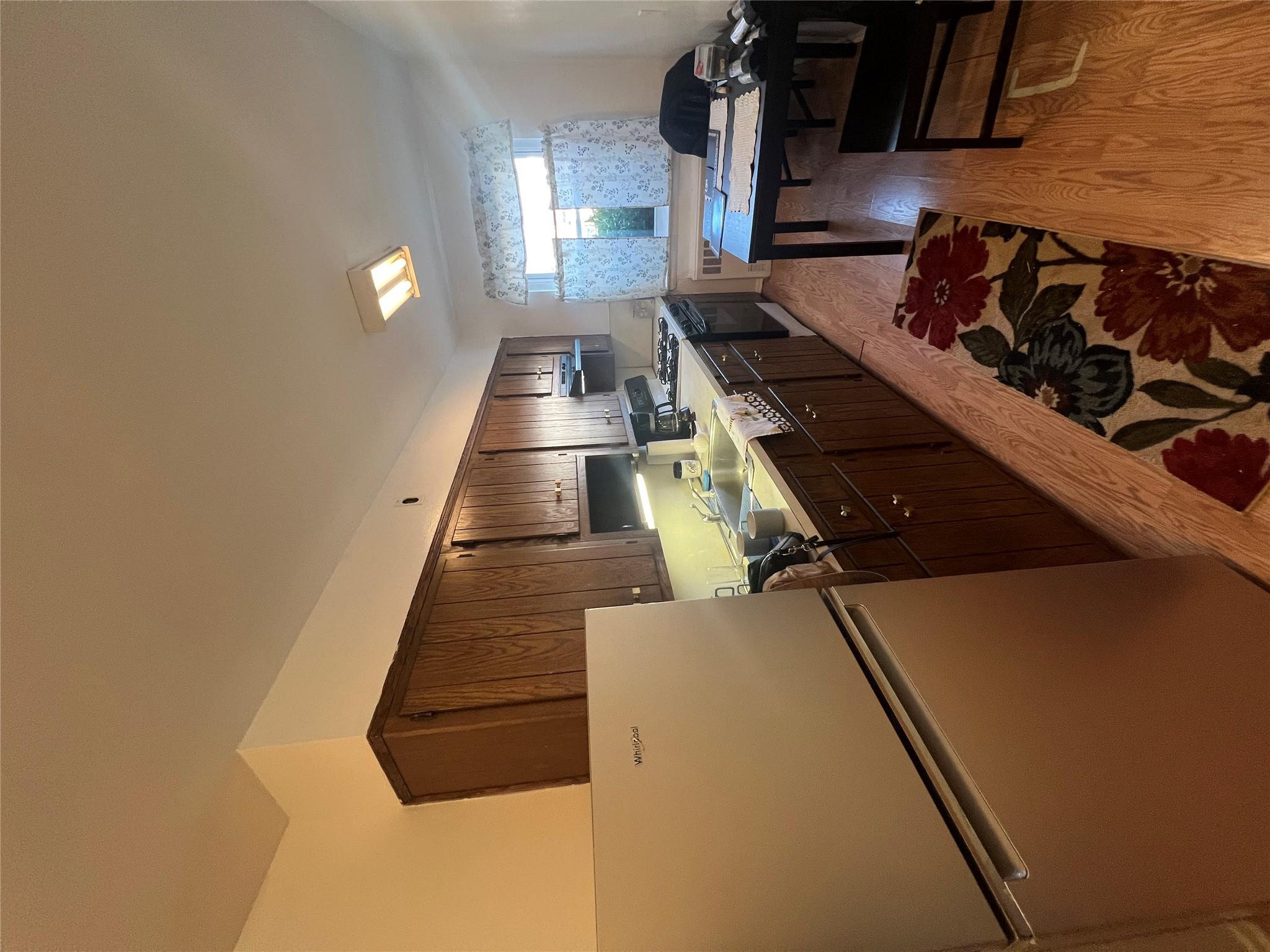 41-20 210th Street, Unit 1 Queens, NY 11361 - Photo 4 of 17 Kitchen featuring dark brown cabinetry, refrigerator, a sink, light wood-style flooring, and range