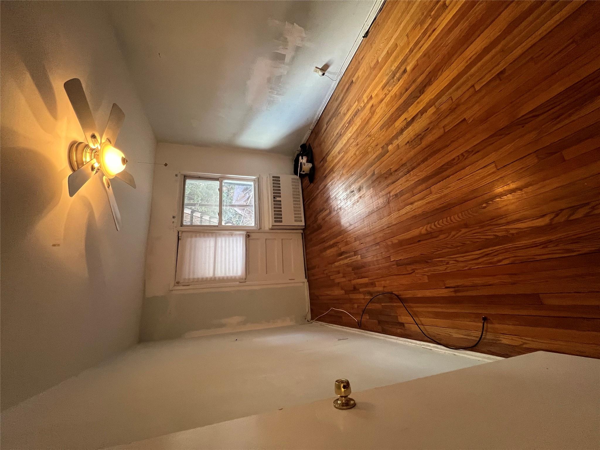 41-20 210th Street, Unit 1 Queens, NY 11361 - Photo 7 of 17 Empty room with radiator, wood-type flooring, and a ceiling fan