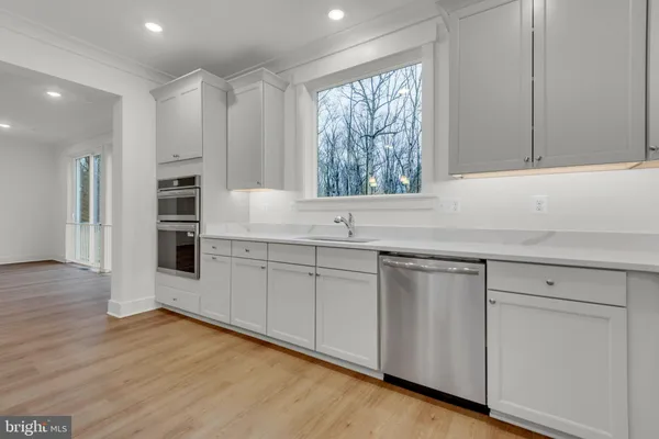 a kitchen with stainless steel appliances granite countertop a refrigerator a sink dishwasher and a oven with white cabinets